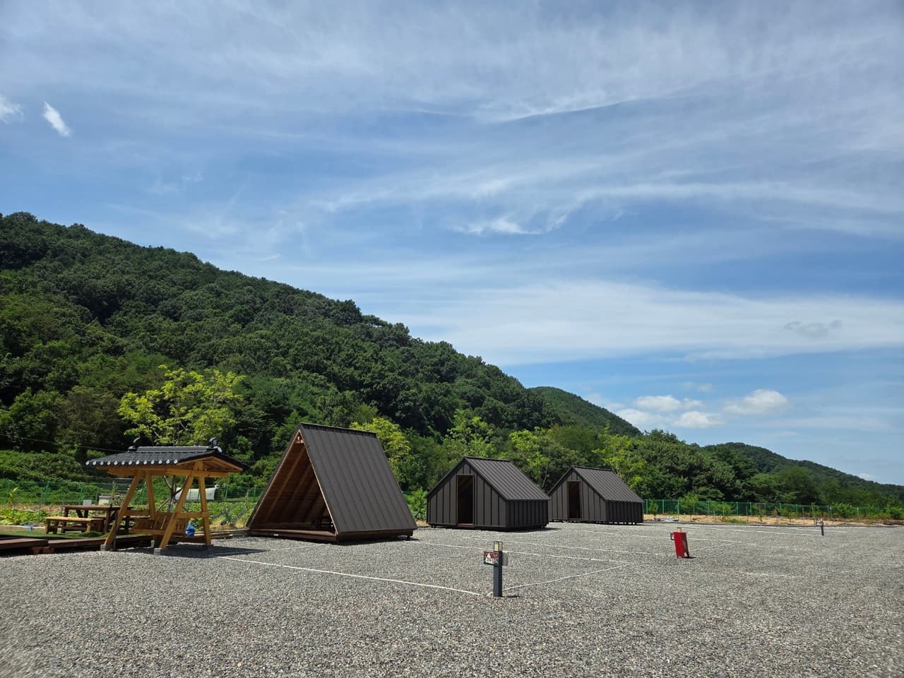 砕石の上に建つ3棟のキャビンと背後の山